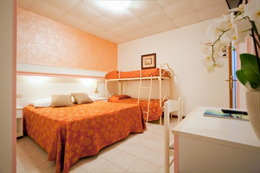 A dormitory room with two beds, a desk, and a chair.