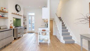 A modern kitchen with wooden flooring, built-in appliances, and a staircase leading to a second floor. - Vauxhall Oasis - 3 Bed House by BaseToGo (London)