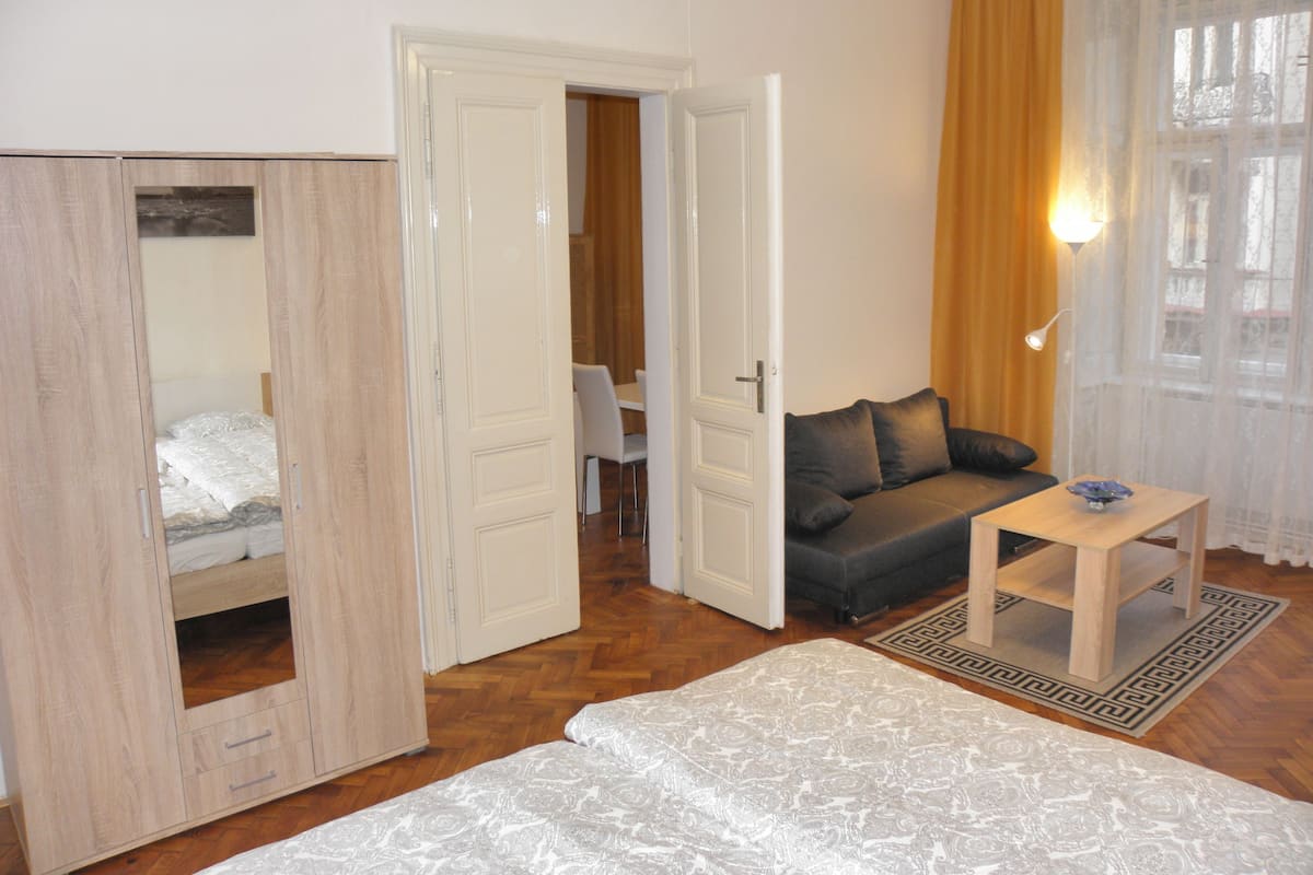 A room with a bed, a sofa, a small table, and a wardrobe.