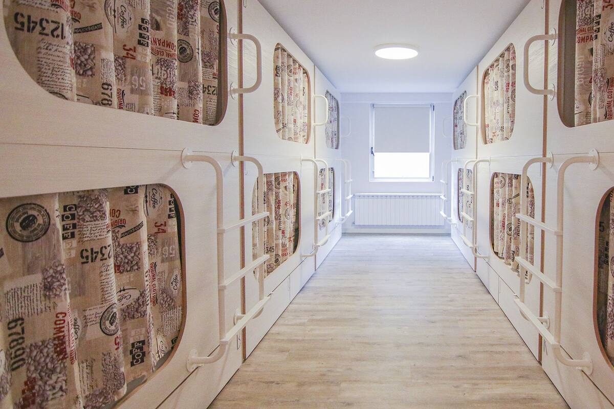 Pasillo con literas cubiertas de sacos de café, que conduce a una ventana.