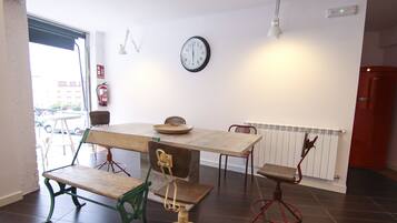 Uma área de refeições com mesa de madeira, bancos, relógio e radiador.