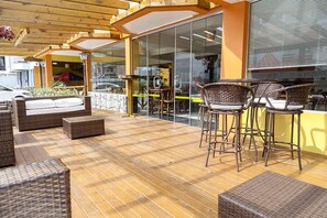 An outdoor seating area with wicker furniture and a wooden deck. - Apart Hotel Fênix (Florianópolis)