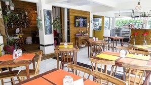 A restaurant with wooden tables and chairs, a bar area, and a TV mounted on the wall. - Apart Hotel Fênix (Florianópolis)