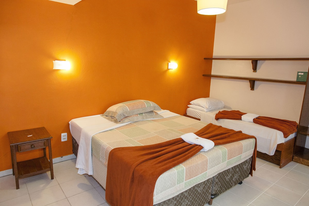 Une chambre d’hôtel avec deux lits, une table de chevet et une étagère avec des serviettes.