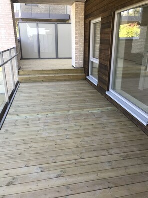 A wooden deck with a glass door and a brick wall.