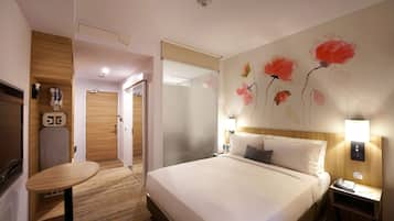 Une chambre d’hôtel avec un grand lit, une petite table, une table de chevet avec une lampe et un mur décoré d’œuvres d’art florales.