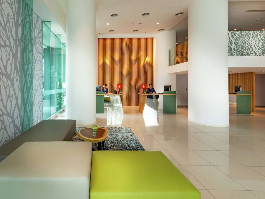Un moderno vestíbulo con mostrador de recepción, zonas de estar y una pared decorativa con líneas verticales.