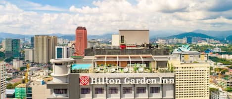 Un bâtiment de l’hôtel Hilton Garden Inn doté d’une piscine sur le toit et offrant une vue sur le paysage urbain.
