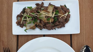 Un plato de arroz con salteado de carne y una bebida tropical sobre una mesa de madera.
