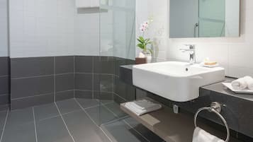 A modern bathroom with a glass shower enclosure, a white sink, and a large mirror.