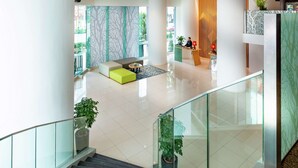 A modern hotel lobby with a staircase, seating area, and reception desk. - Hilton Garden Inn Kuala Lumpur Jalan Tuanku Abdul Rahman South (Kuala Lumpur)