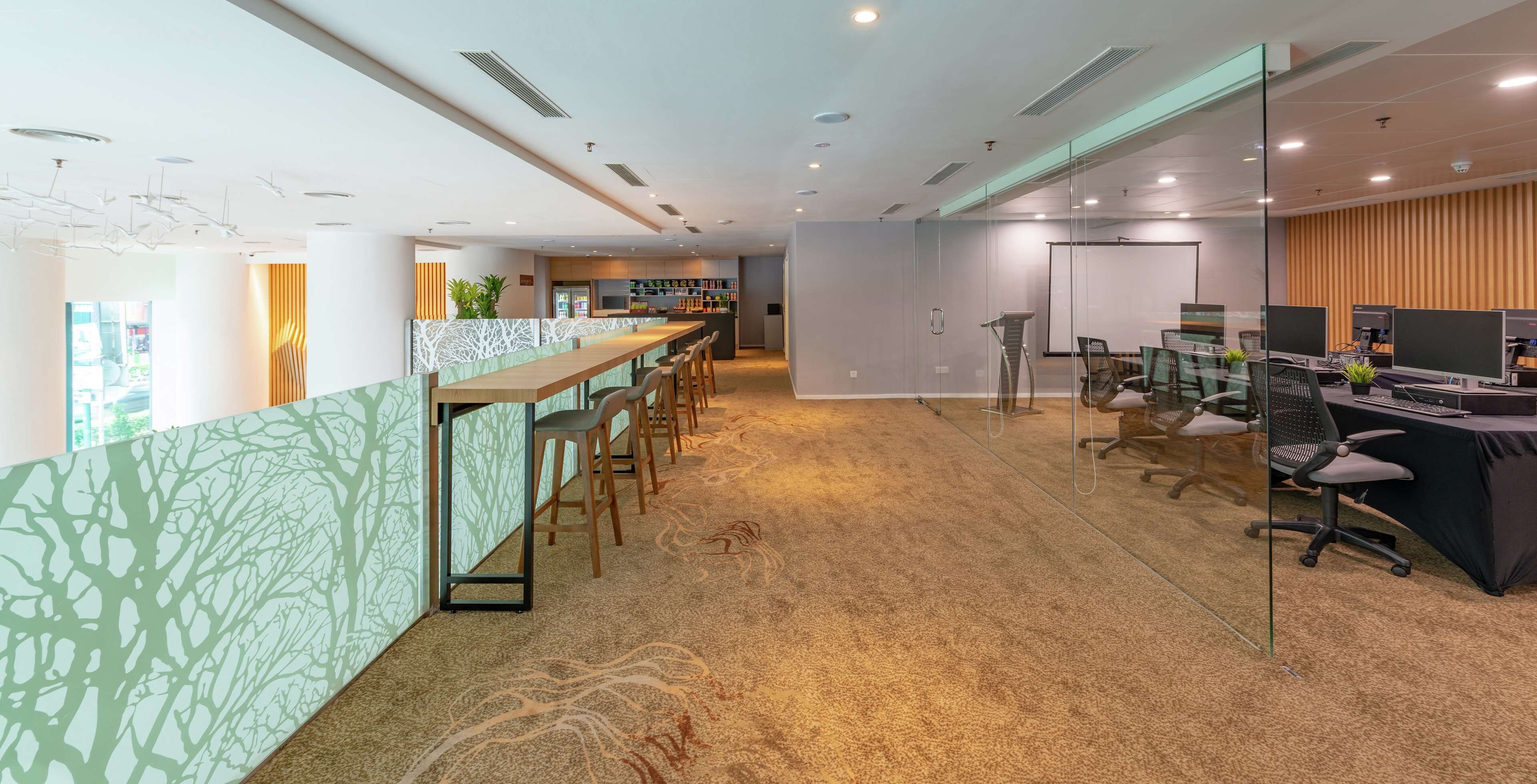 A modern office space with a long reception desk, multiple workstations, and a carpeted floor.