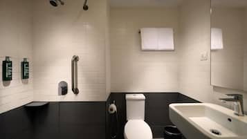 Een moderne badkamer met een wit toilet, een zwart bad, een witte wastafel en een douche.