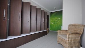A row of dark wooden lockers, a wicker chair, and a green wall with a plant. - Apartmány Pod Zálesím (Loucna nad Desnou)