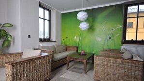 A room with wicker furniture, a green wall mural, and large windows. - Apartmány Pod Zálesím (Loucna nad Desnou)