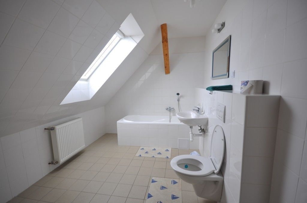Moderni kylpyhuone, jossa on kattovalokuvio, kylpyamme, pesuallas ja wc.