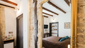 A bedroom with a large mirror, wooden beams, a bed, a bedside table, and a dresser. - Luxury Rooms Contessa Vitali (Zadar)