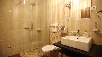 A bathroom with a shower, toilet, sink, and a mirror.