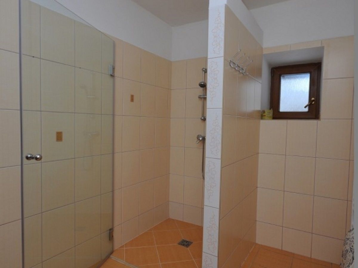 A bathroom with a glass shower enclosure, tiled walls, and a small window.