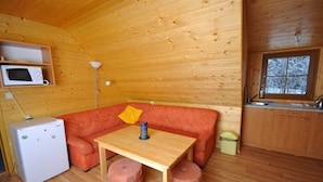 A compact cabin with a wooden interior, a sofa, a small table, a microwave, a lamp, and a window. - Chata Pod Vlekem (Loucna nad Desnou)