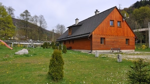 A wooden house with a sloped roof, a satellite dish, and a bench in the yard. - Chata Pod Vlekem (Loucna nad Desnou)
