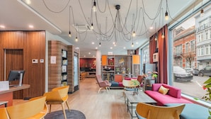 A modern hotel lobby with wooden paneling, a reception desk, seating areas, and large windows offering city views. - Appart'City Confort Bruxelles Centre Gare du Midi (Brussels)