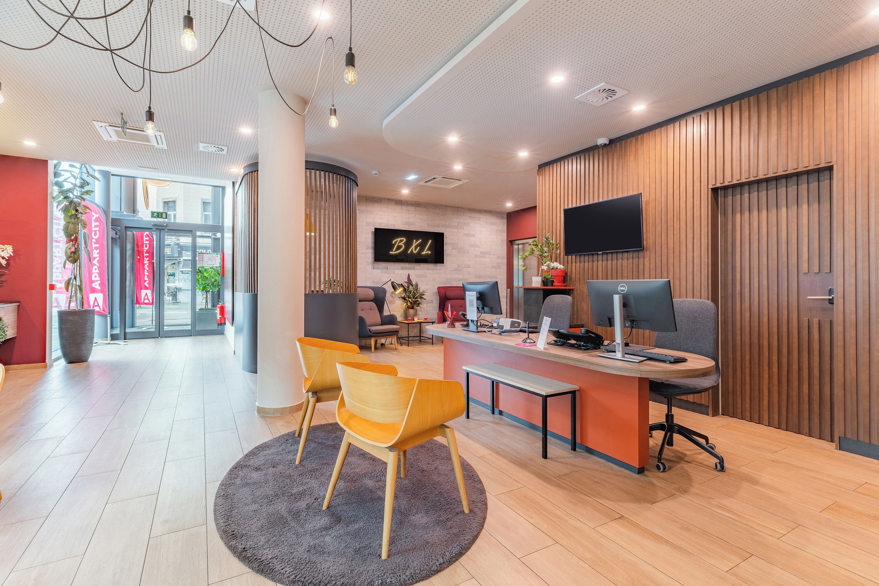 A reception area with a desk, chairs, a TV, and a sign that reads 'BXL'.