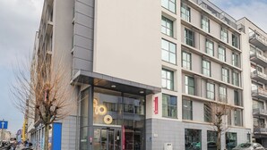 A modern building with a glass entrance, a visible sign, and a parked car. - Appart'City Confort Bruxelles Centre Gare du Midi (Brussels)