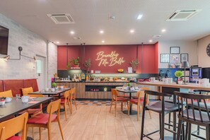 A restaurant with a red wall, wooden tables, and chairs. - Appart'City Confort Bruxelles Centre Gare du Midi (Brussels)