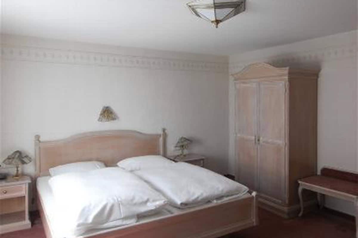 Une chambre à coucher avec un lit en bois, une table de chevet, une lampe et une armoire.