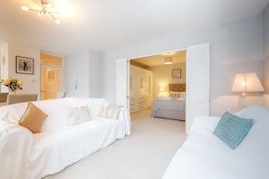 A hotel room with two beds, a sitting area, and a bathroom visible through an open door. - Putney Court - 1 Bed Apartment by BaseToGo (London)