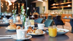 A breakfast setting with croissants, pastries, and a glass of orange juice on a table. - Hotel Am Kloster (Werne)