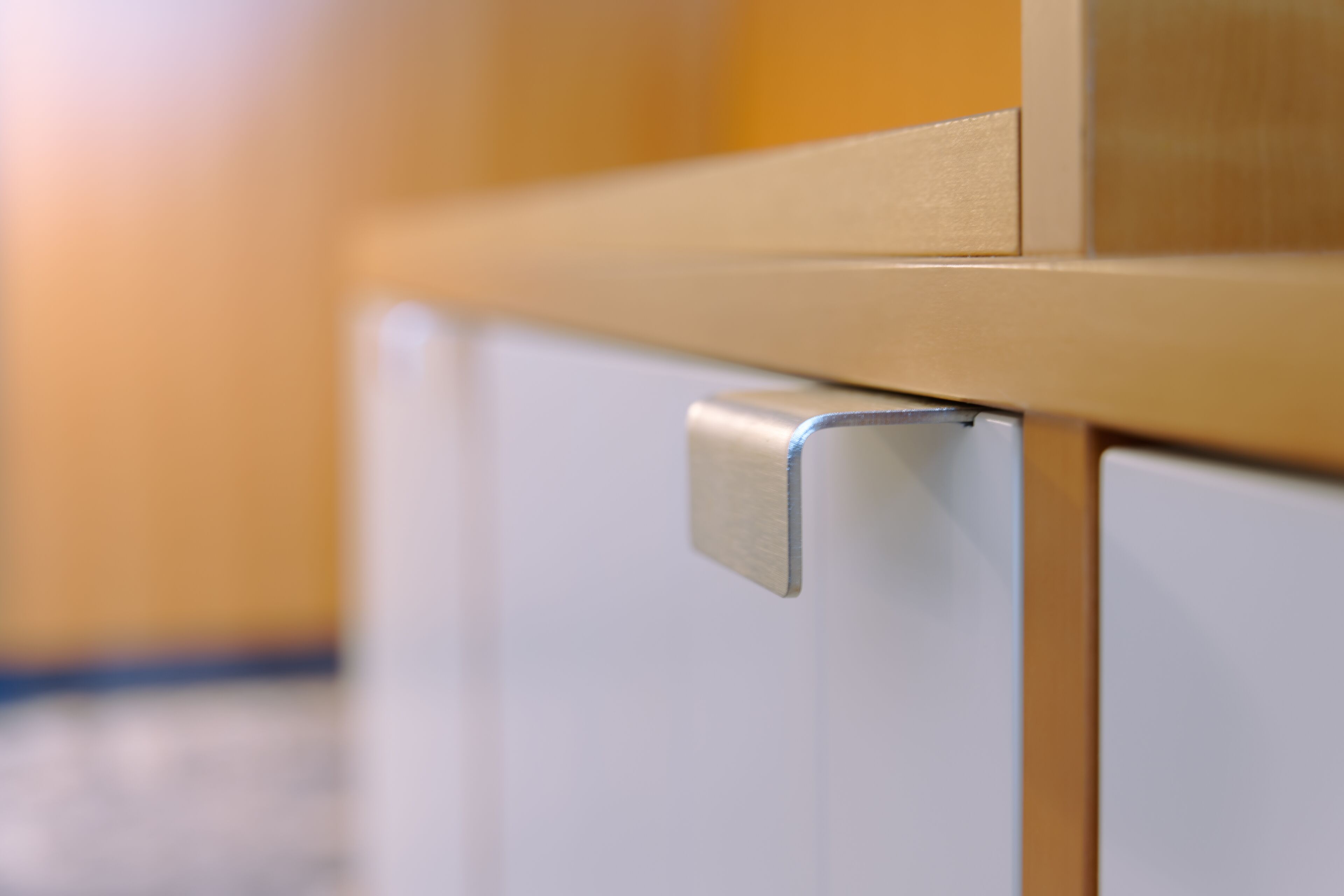 A close-up of a metallic handle attached to a wooden structure, likely part of a door or cabinet.