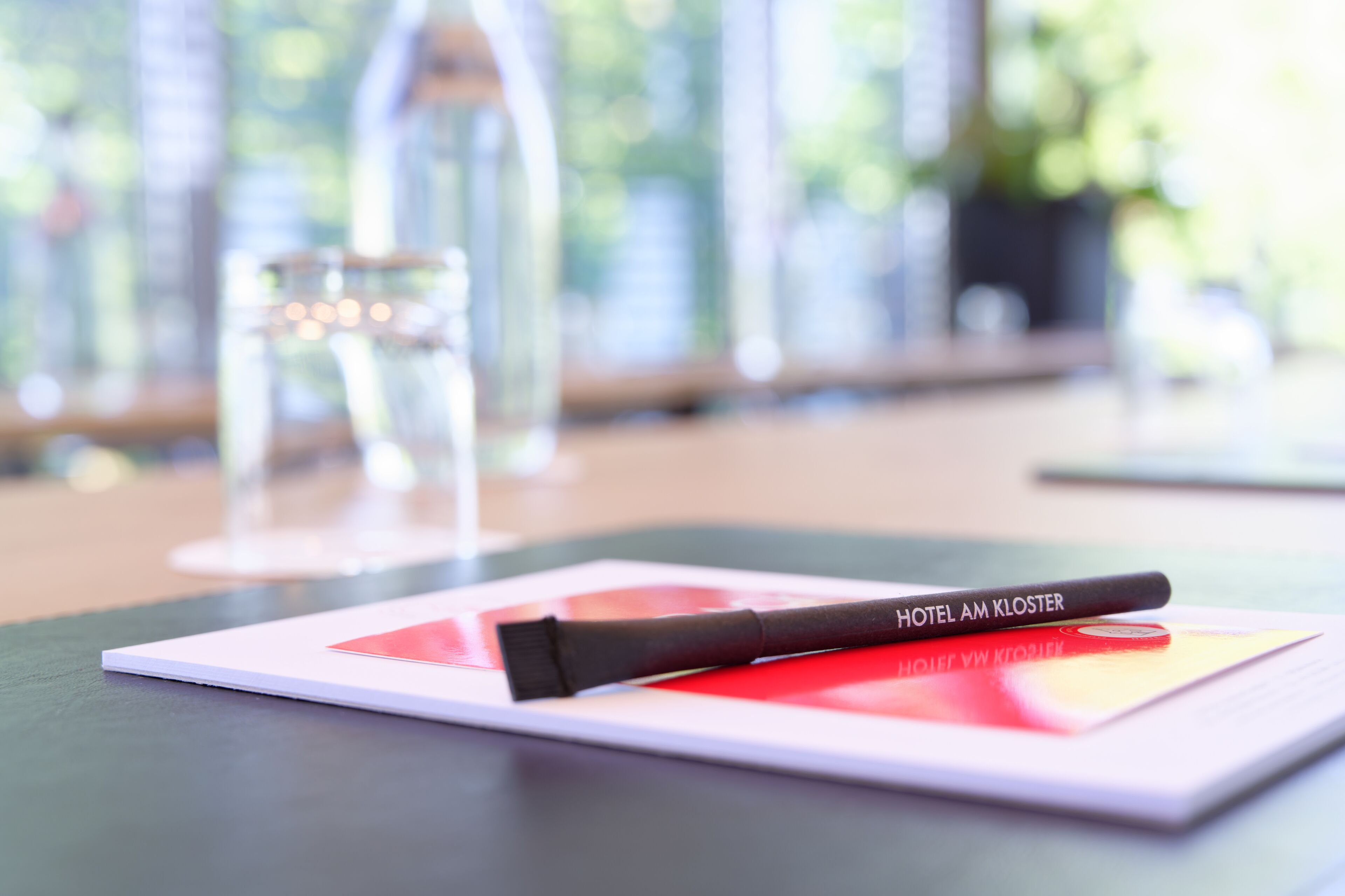 A hotel brochure on a table with a pen and a glass of water.