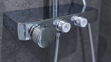 A chrome shower control panel with two knobs and a hose.
