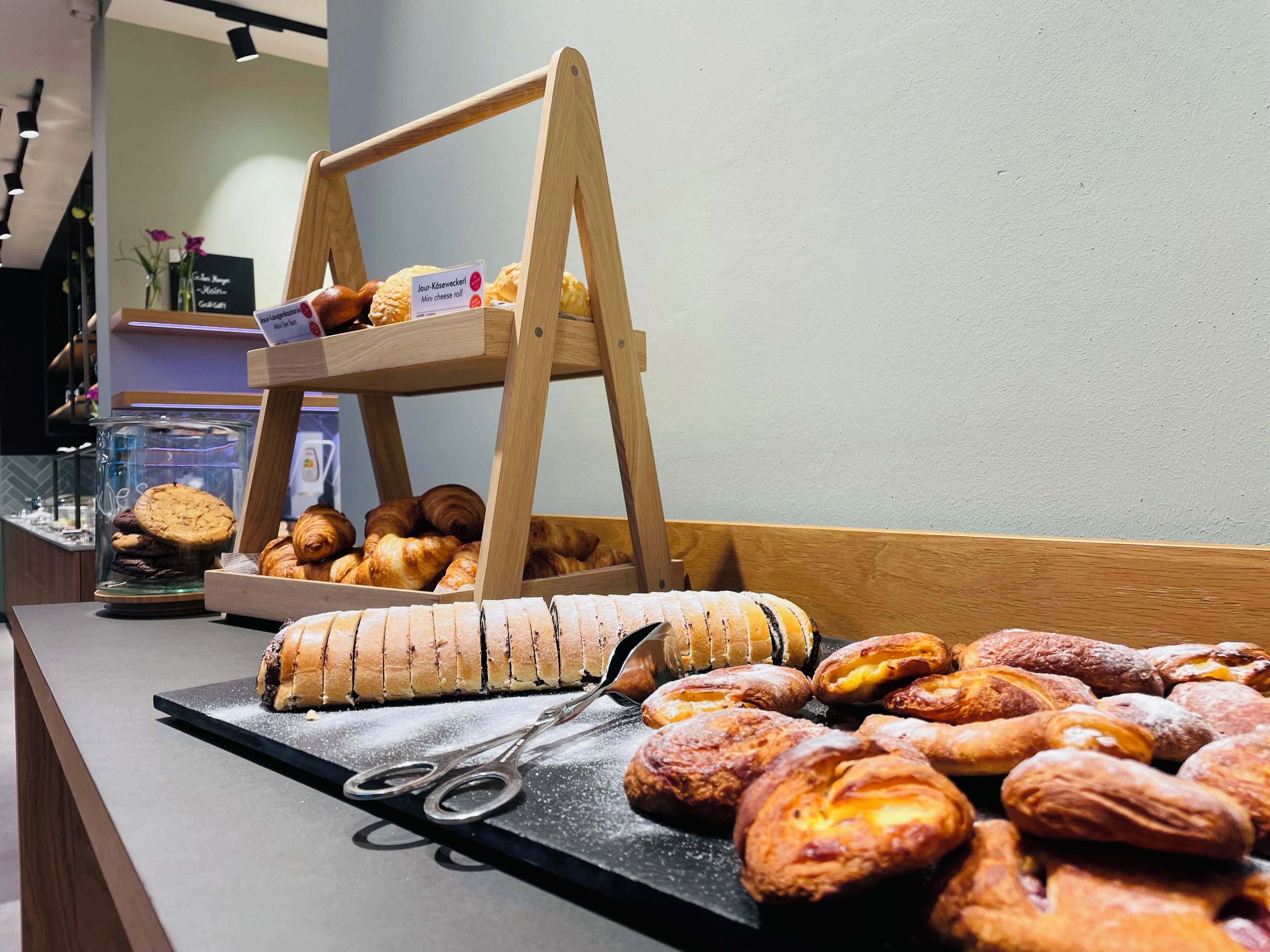 A bakery display with various pastries and a sign indicating a mini cheese roll.