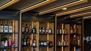 A bar with wooden shelves stocked with various liquor bottles and glasses. - Hotel Am Kloster (Werne)