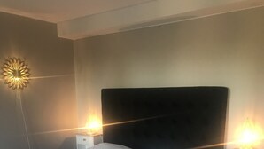 A neatly made bed with white linens, two bedside tables with lamps, and a modern wall light fixture. - Park Hotell (Lycksele)