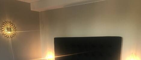 A neatly made bed with white linens, two bedside tables with lamps, and a modern wall light fixture.