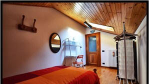 Una camera da letto con un letto, una sedia, un termosifone, uno specchio e un appendiabiti.