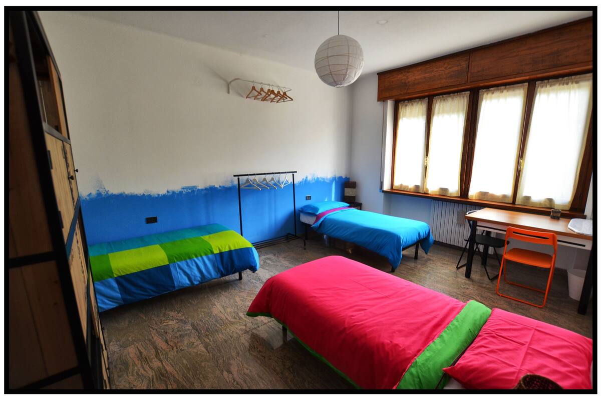A dormitory room with two single beds, a desk, and a chair.