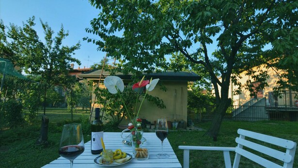Un tavolo all'aperto con bicchieri da vino, una bottiglia e cibo.