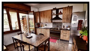 Una cucina con mobili in legno, un frigorifero in acciaio inossidabile, un fornello e un tavolo da pranzo con sedie.
