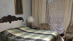 A bedroom with a bed, a chair, a chandelier, curtains, and a framed picture on the wall. - B&B Luisa (Bergamo)