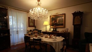 A dining room with a chandelier, a table set for four, and a clock on the wall. - B&B Luisa (Bergamo)