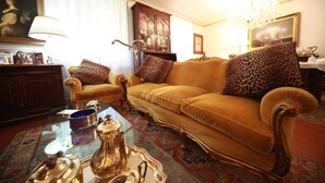 A living room with a sofa, armchairs, a glass coffee table, and a patterned rug. - B&B Luisa (Bergamo)