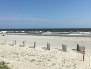 A beach with a sandy area, a wooden fence, and the ocean in the background. - Tailslide Inn 4 Bedroom Home by RedAwning (Supply)