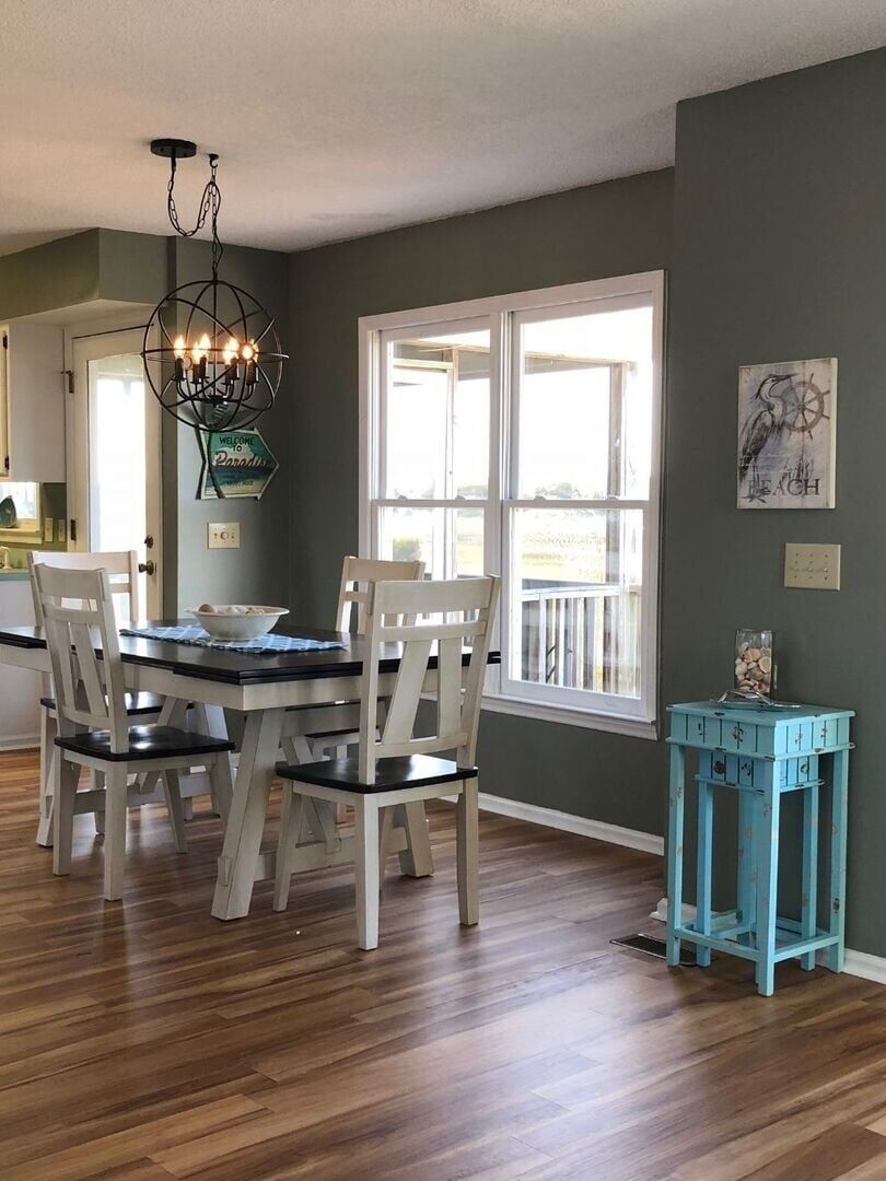 A dining area with a table and chairs, a chandelier, a window, and a small blue table.