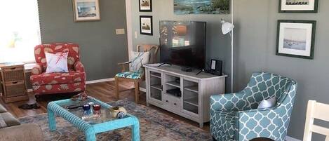 Una sala de estar con una mesa de comedor, sillas, un televisor y un ventilador de techo.