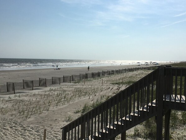 A beach with a wooden fence and a staircase leading down to the sand.